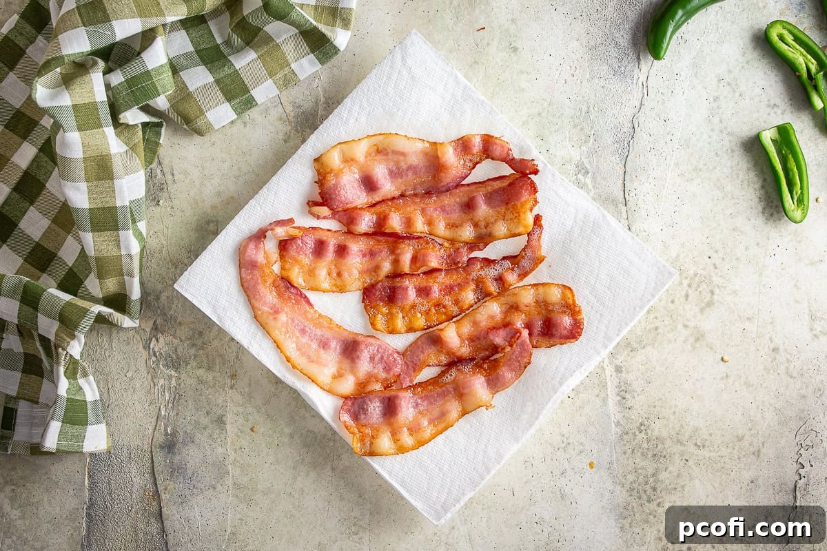 Partially cooked bacon on a paper towel draining.