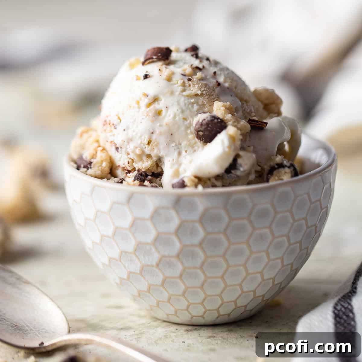 Homemade cookie dough ice cream scooped into a white ceramic bowl, showing generous chunks of cookie dough.