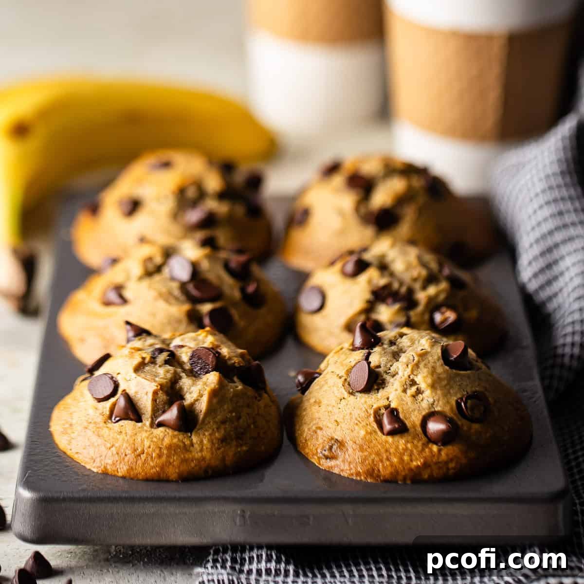 A pan of freshly baked banana chocolate chip muffins with golden-brown tops.