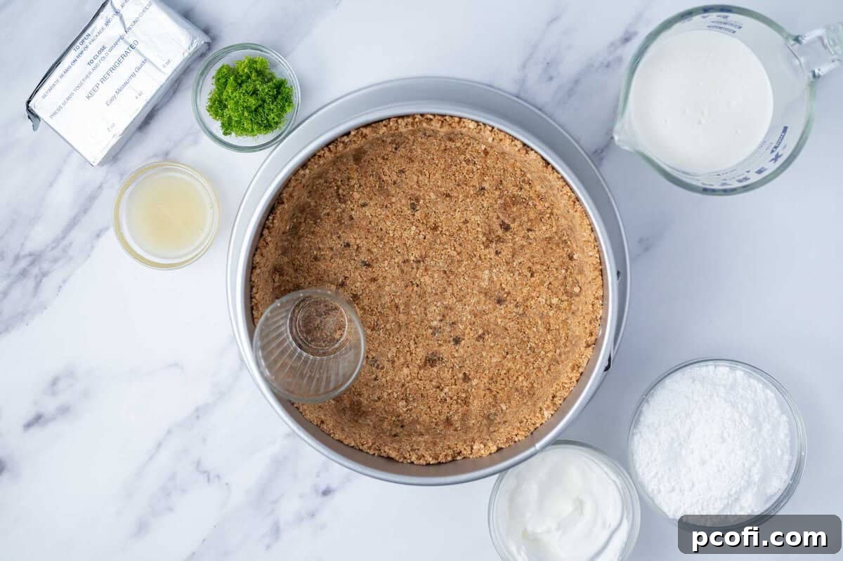 graham cracker crust being pressed into a springform pan with a cup