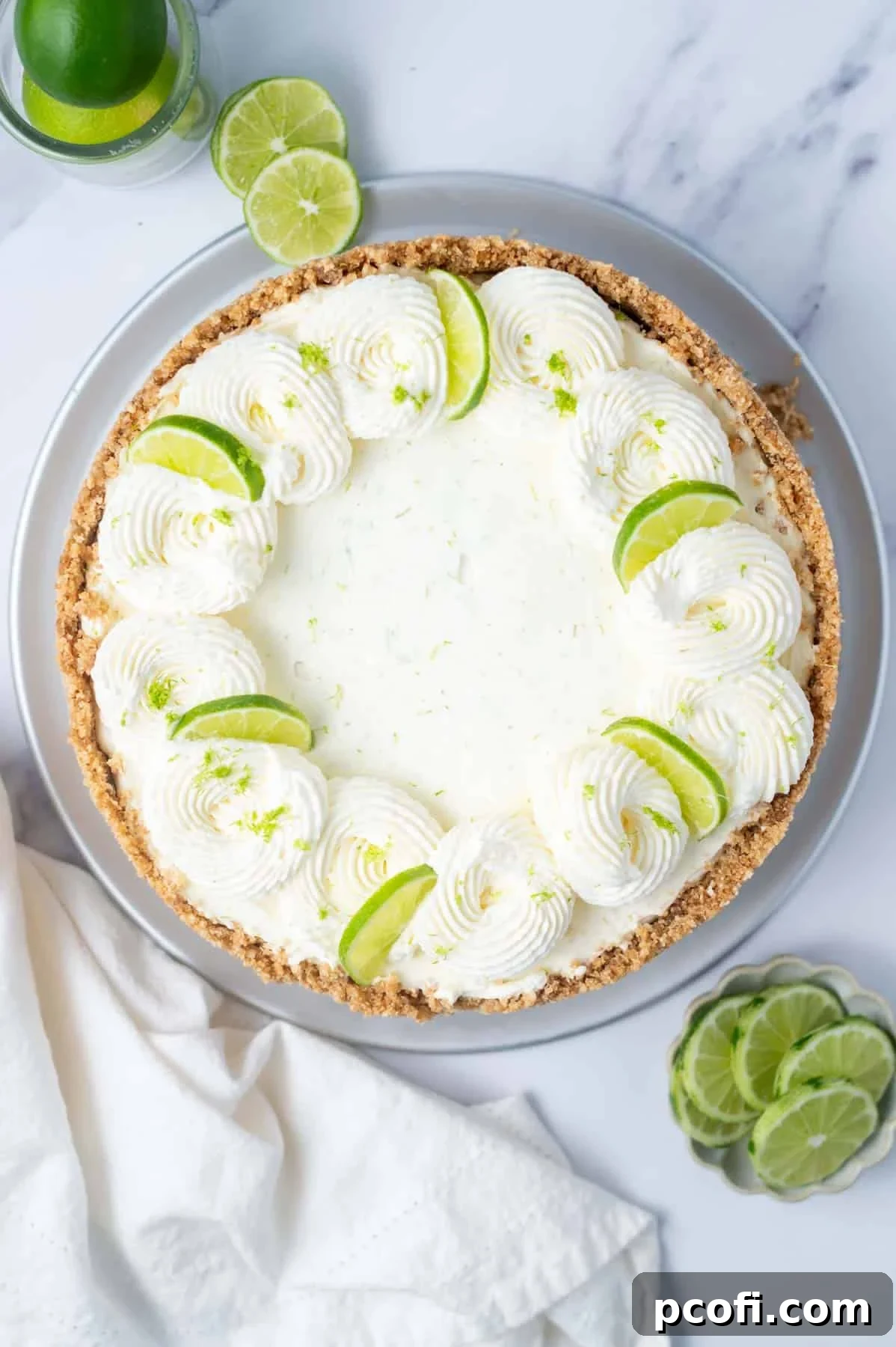 overhead look at key lime cheesecake with whipped cream swirls and lime slices