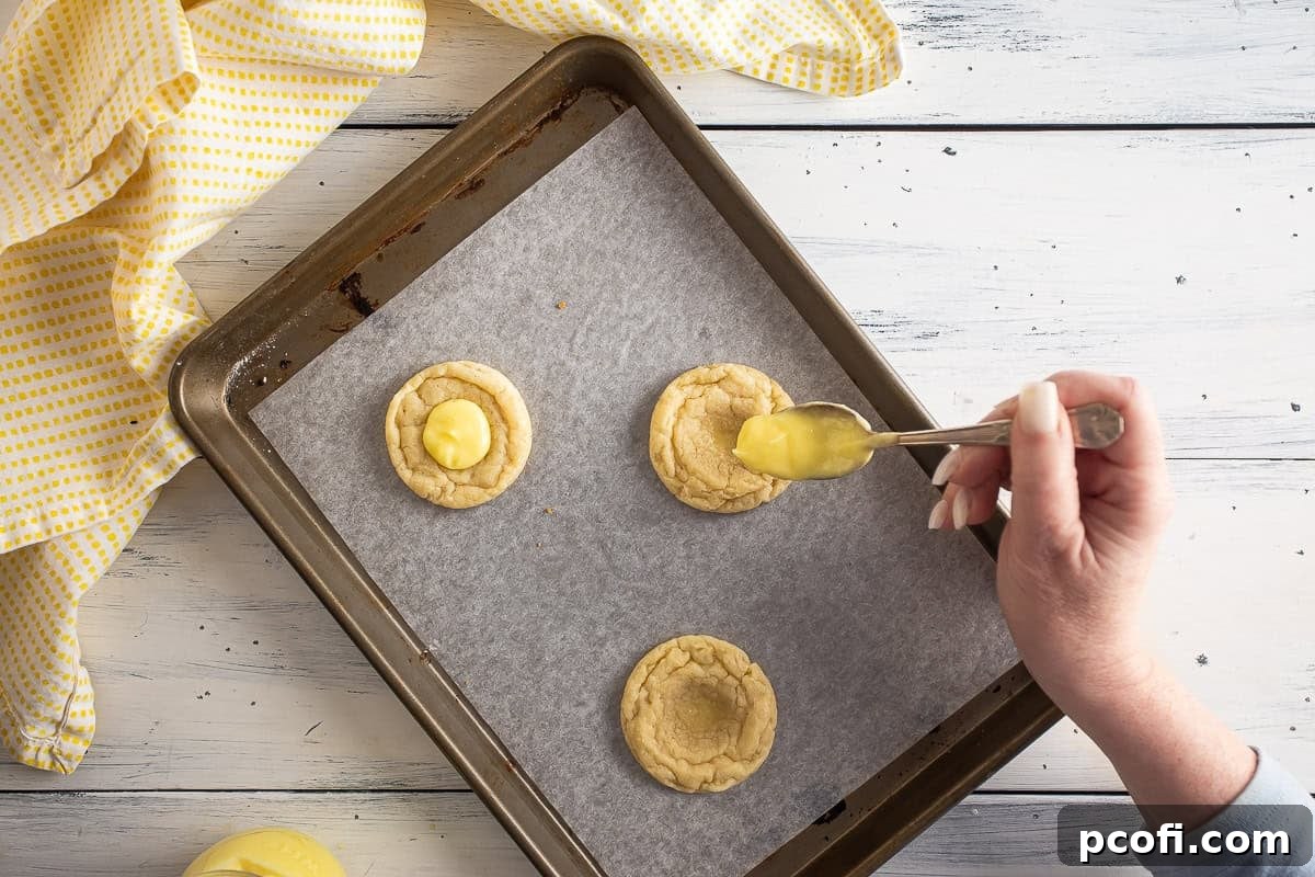 Adding lemon curd to the shaped cookies.