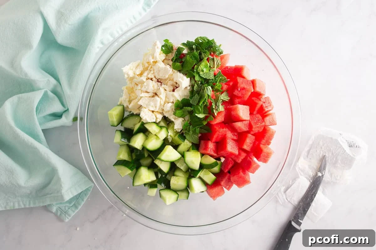 Refreshing Watermelon, Feta & Mint Salad Recipe 6 Ingredients for watermelon salad in a glass bowl before being mixed.