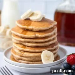 stack of pancakes on a plate with syrup and banana slices