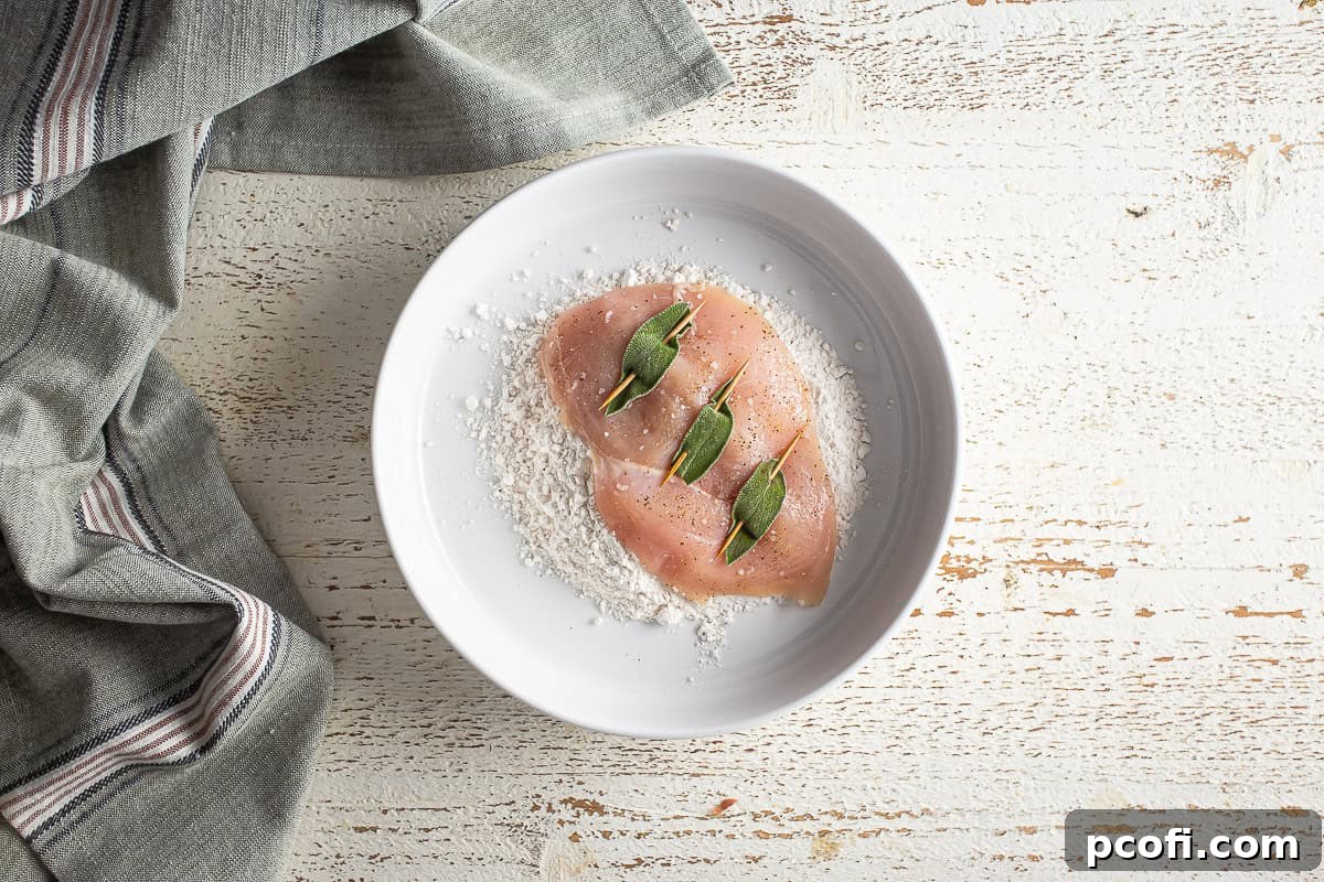 Dusting a chicken breast for chicken saltimbocca with flour.
