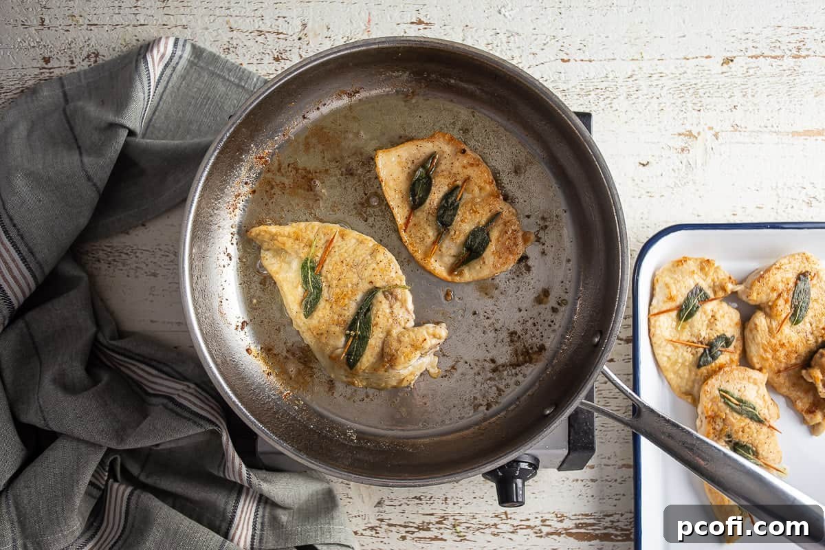 Cooking chicken breast in a stainless steel skillet.