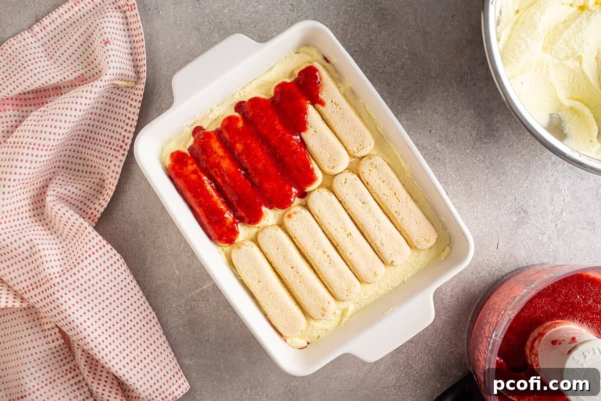 Strawberry Tiramisu Recipe with Mascarpone and Ladyfingers 16 Adding strawberry puree to the second layer of strawberry tiramisu.