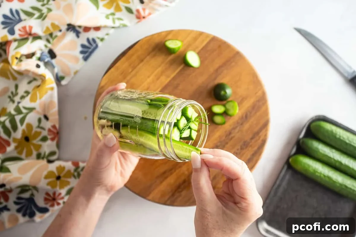 Homemade Dill Pickles: Crispy Refrigerator and Canning Recipes 5 Stuffing sliced dill pickles on a glass canning jar.